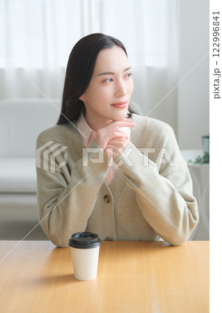 テーブルに座ってオフィスの窓から外を見るビジネスウーマン 　　　　　 122996841