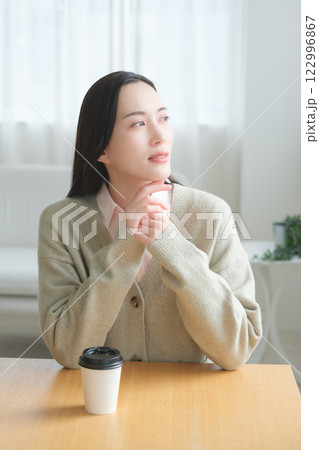 テーブルに座ってオフィスの窓から外を見るビジネスウーマン 　　　　　 122996867