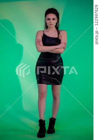 A Stylish Woman Dressed in a Black Dress Poses Elegantly Against a Stylish Green Background A Stylish Woman Dressed in a Black Dress Poses Elegantly Against a Stylish Green Background 122997829