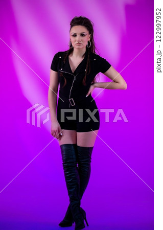 A Fashion Model Dressed in an Edgy Outfit, Posed Elegantly Against a Purple Background A Fashion Model Dressed in an Edgy Outfit, Posed Elegantly Against a Purple Background 122997952