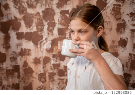 A Child Delightfully Enjoying a Warm Beverage While Seated Against a Textured Background 122998089