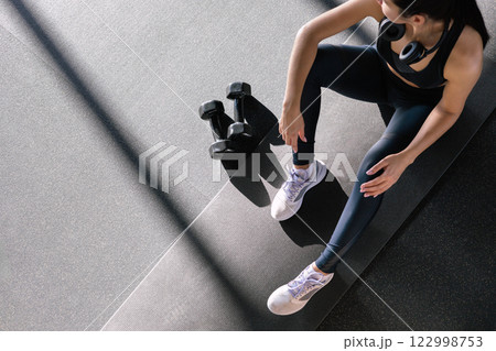 Fitness asian woman legs sitting on sport mat training with dumbbells closeup top view. 122998753