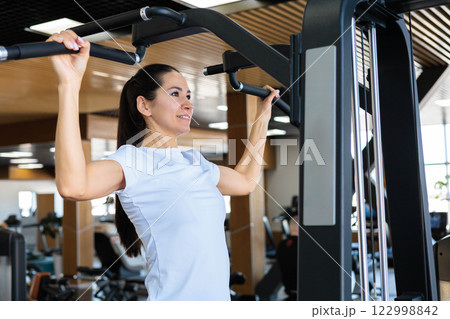 Young beautiful Asian woman with athletic build and good figure doing pull-ups  122998842