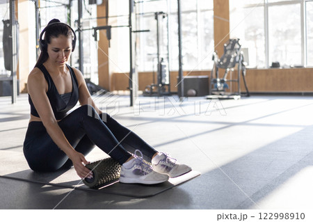 Strong beautiful fitness woman asian exercising legs, massaging herself with self massage roller 122998910