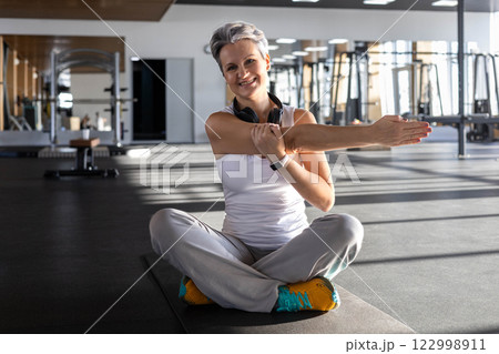 Athletic fitness An elderly gray-haired senior pensioner of age stretching body at gym 122998911