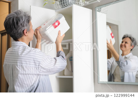 Beautiful elderly woman pensioner with gray hair putting first aid kit with vitamins, drugs 122999144