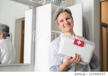 Beautiful elderly woman pensioner with gray hair putting first aid kit with vitamins, drugs 122999147