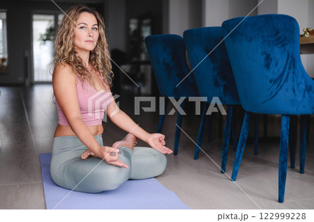 Yoga woman meditation in lotus pose with signing bowl sitting on mat at home 122999228