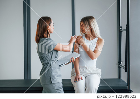Concentrated on working on arms. Woman is in health center getting help by doctor 122999622