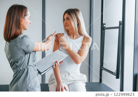 Concentrated on working on arms. Woman is in health center getting help by doctor 122999623