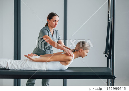 Laying down on stomach. Woman is in health center getting help by doctor Laying down on stomach. Woman is in health center getting help by doctor 122999646