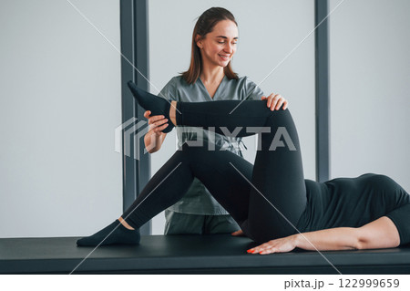 Active exercises. Woman is in health center getting help by doctor 122999659