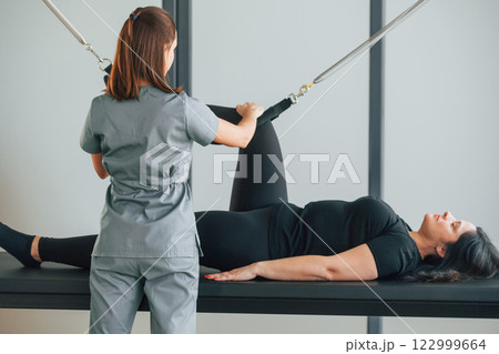 Legs is on the stretching cable. Woman is in health center getting help by doctor 122999664