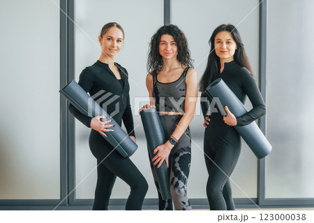 Holding yoga mats. Women in sportive clothes standing in the fitness center Holding yoga mats. Women in sportive clothes standing in the fitness center 123000038
