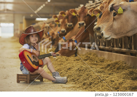 Charming child in a cowboy costume sings for cows on a farm in Denmark 123000167