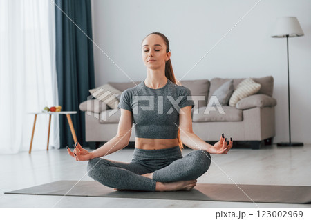 Lotus pose. Young woman with slim body type and in yoga clothes is at home 123002969