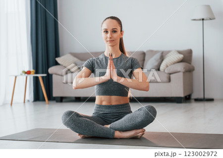 Lotus pose. Young woman with slim body type and in yoga clothes is at home 123002972