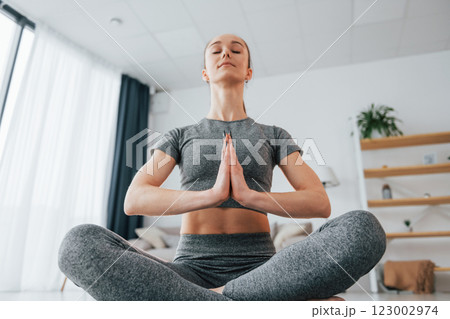 Sitting on the floor. Young woman with slim body type and in yoga clothes is at home Sitting on the floor. Young woman with slim body type and in yoga clothes is at home 123002974