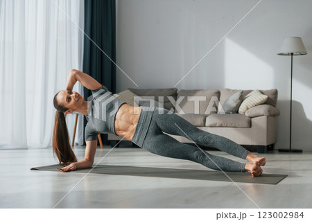 Stretching exercises. Young woman with slim body type and in yoga clothes is at home 123002984