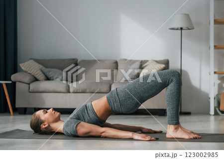 Stretching exercises. Young woman with slim body type and in yoga clothes is at home 123002985