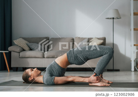 Stretching exercises. Young woman with slim body type and in yoga clothes is at home Stretching exercises. Young woman with slim body type and in yoga clothes is at home 123002986