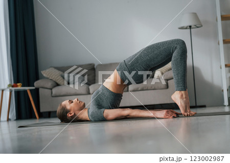 Stretching exercises. Young woman with slim body type and in yoga clothes is at home Stretching exercises. Young woman with slim body type and in yoga clothes is at home 123002987