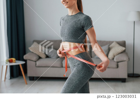 Concept of dieting. Young woman with slim body type and in yoga clothes is at home Concept of dieting. Young woman with slim body type and in yoga clothes is at home 123003031