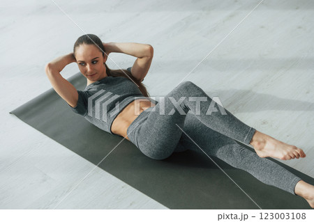 Strong abs. Young woman with slim body type and in yoga clothes is at home Strong abs. Young woman with slim body type and in yoga clothes is at home 123003108