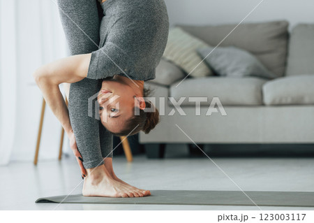 Close up view. Young woman with slim body type and in yoga clothes is at home Close up view. Young woman with slim body type and in yoga clothes is at home 123003117