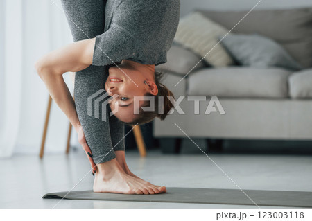 Big stretches. Young woman with slim body type and in yoga clothes is at home Big stretches. Young woman with slim body type and in yoga clothes is at home 123003118
