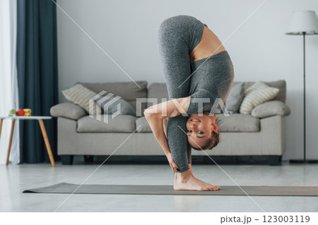 Big stretches. Young woman with slim body type and in yoga clothes is at home 123003119