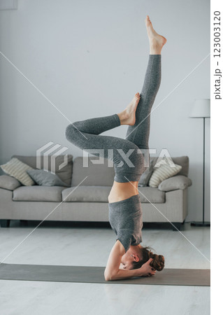 Big stretches. Young woman with slim body type and in yoga clothes is at home 123003120