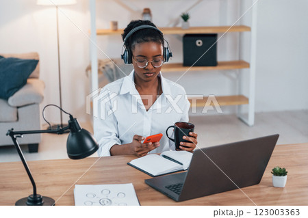 Working from home. Young african american woman in white shirt Working from home. Young african american woman in white shirt 123003363