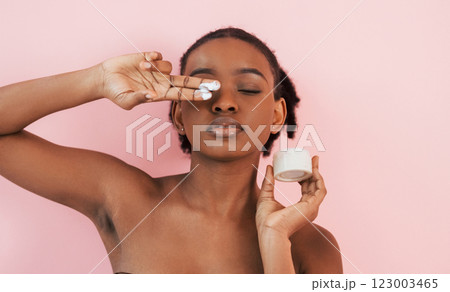 Conception of skin care. Portrait of young african american woman that is against pink background Conception of skin care. Portrait of young african american woman that is against pink background 123003465