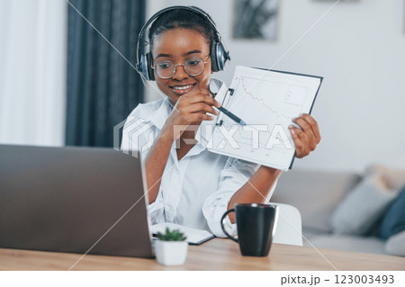 Busy by doing online order. Young african american woman in white shirt is at home 123003493