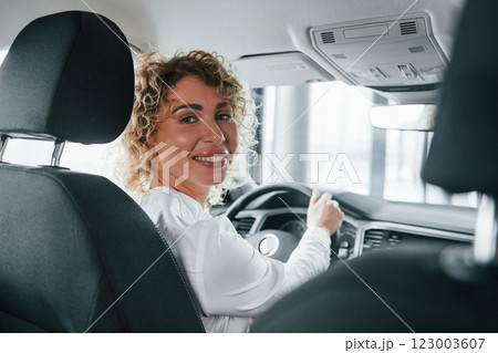 Rear view. Woman with curly blonde hair is in autosalon Rear view. Woman with curly blonde hair is in autosalon 123003607