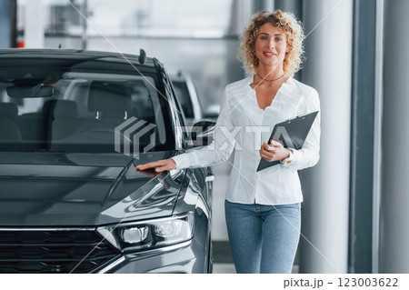 Holding notepad. Woman with curly blonde hair is in autosalon Holding notepad. Woman with curly blonde hair is in autosalon 123003622