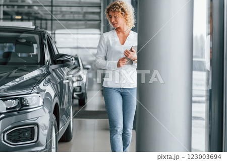 In official white shirt. Woman with curly blonde hair is in autosalon 123003694