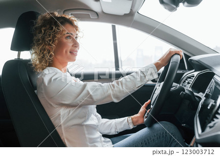 Doing test drive. Woman with curly blonde hair is in autosalon 123003712
