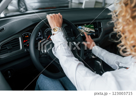 Doing test drive. Woman with curly blonde hair is in autosalon 123003715