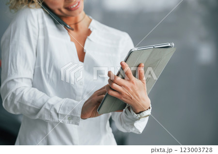 Tablet is in the hands. Woman with curly blonde hair is in autosalon 123003728