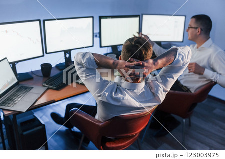 Analizing graphs together. Two stock traders working in the office with exchange technology Analizing graphs together. Two stock traders working in the office with exchange technology 123003975