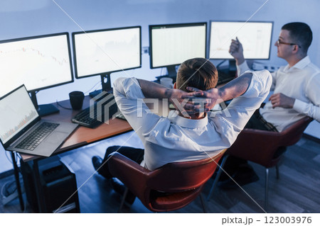 Analizing graphs together. Two stock traders working in the office with exchange technology Analizing graphs together. Two stock traders working in the office with exchange technology 123003976