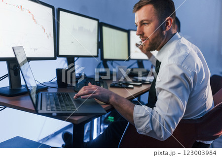 With laptop on the table. Two stock traders working in the office with exchange technology With laptop on the table. Two stock traders working in the office with exchange technology 123003984