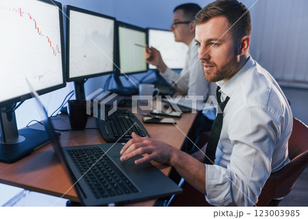 With laptop on the table. Two stock traders working in the office with exchange technology With laptop on the table. Two stock traders working in the office with exchange technology 123003985