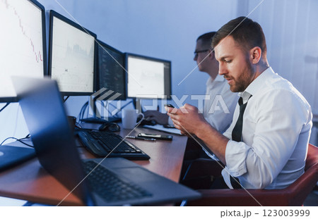 Many displays on the table. Two stock traders working in the office with exchange technology Many displays on the table. Two stock traders working in the office with exchange technology 123003999