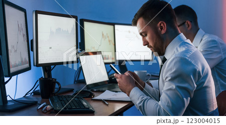 Side view. Two stock traders working in the office with exchange technology 123004015