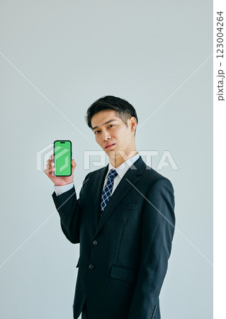 スマホを持つ20代の若い男性　グリーンバック 123004264