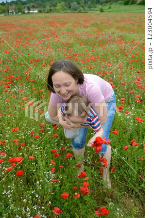 Little boy and his mother in a huge field of wild red poppies 123004594