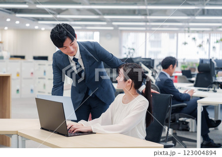 オフィスのデスクで打ち合わせをする男女のビジネスパーソン オフィスのデスクで打ち合わせをする男女のビジネスパーソン 123004894